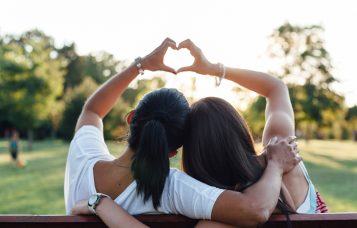 two women gesturing a heart sign