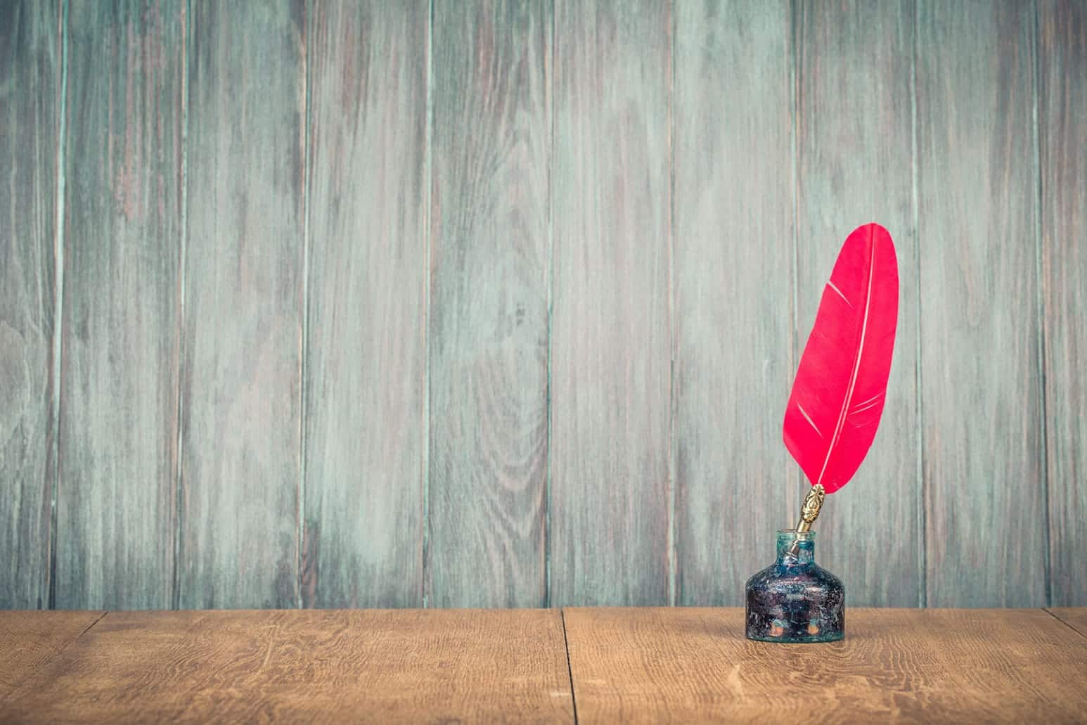 a red feather ink pen on top of a table