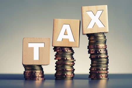 tax in wooden blocks on top of a stack of coins