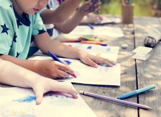 children drawing on top of a table